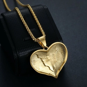Macro d'un pendentif coeur doré avec relief texturé sur une boîte à bijoux noire