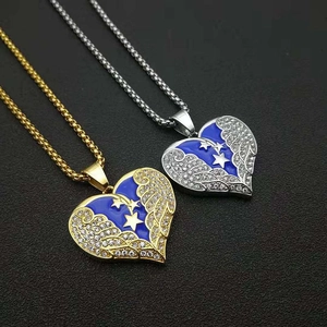 Détail de pendentifs ailes de cœur or et argent avec émail bleu et strass scintillants
