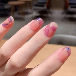 Artistic press-on nails with soft pink base, purple marbling, and golden line details