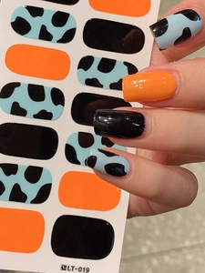 Detailed view of glossy orange, black, and cow print full cover nail art stickers