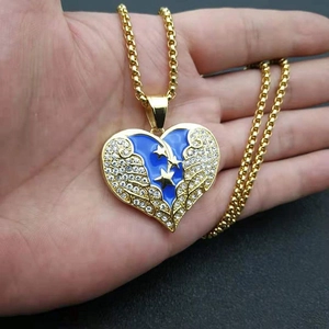Détail du pendentif cœur doré avec émail bleu, ailes scintillantes et étoile sur chaîne