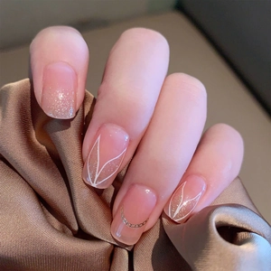 Elegant nude pink gradient press-on nails with white leaf art and gold chain accents