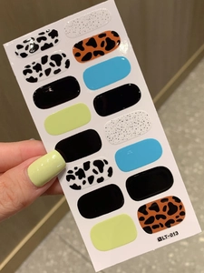 Close-up of leopard and cow print nail stickers with vibrant glossy colors on model's hand