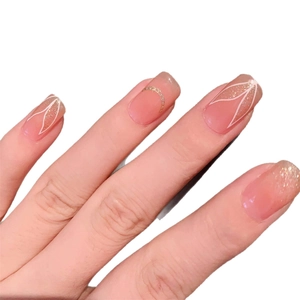 Pink press-on nails with white floral patterns, gold glitter, and chain accents