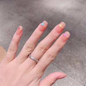 Close-up of nude pink gel nail stickers with colorful floral patterns and white lines