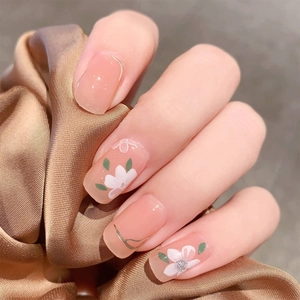 Eleganti unghie finte arancione nudo con fiori bianchi e accenti metallici dorati