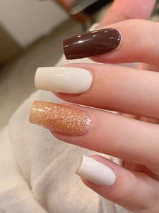 Close-up of gloss solid color nail wraps in brown and cream with glitter accents