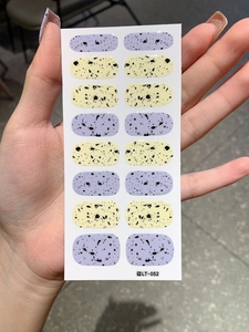 Close-up of Easter egg theme nail stickers in yellow and lilac with black speckles