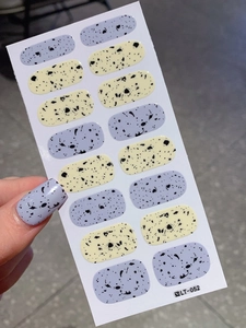 Easter egg pattern nail stickers in purple and yellow colors shown on natural nails