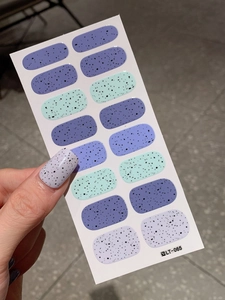 Detailed view of self-adhesive Easter nail stickers with purple and green quail egg patterns