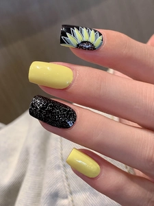 Detail of yellow sunflower nail stickers and black glitter design on square press-on nails