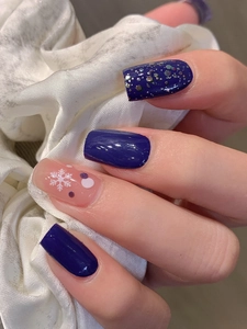 Gros plan d'autocollants pour ongles bleu roi avec flocons et paillettes sur soie