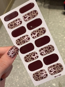 Detail view of dark brown leopard print and solid wine red self-adhesive nail polish wraps