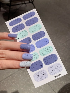 Detail of speckled Easter nail wraps in purple and mint green showing texture and design