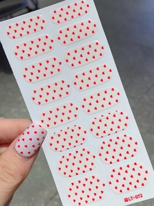 Detail of red heart nail stickers showing full sheet set and application on thumb