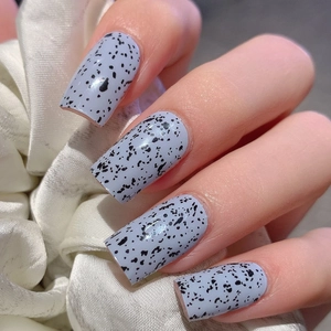 Light blue square press-on nails with black speckled quail egg design on white satin