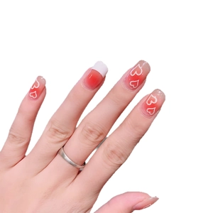 Gradient blush press-on nails with white heart patterns and French tips for manicure