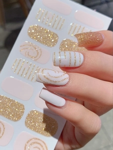 Detail of pink glitter nail stickers featuring golden stripes and spiral patterns for DIY