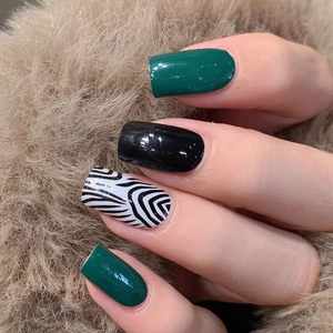 Glossy black, dark green, and zebra print nail stickers on soft faux fur background