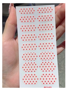 Detail view of model LT-072 nail wraps featuring small red hearts on a translucent base