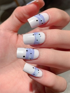 Close-up of long oval press-on nails with white base and purple wave patterns