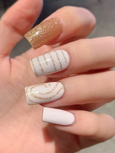 Macro shot of glittery pink nails with gold stripes and minimalist heart patterns