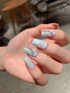 Close-up of minimalist marble nail wraps with grey and speckled art design on hands