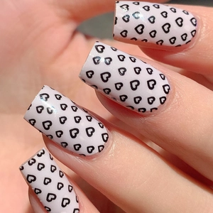 Minimalist white press-on nails with black heart patterns in a square-oval shape