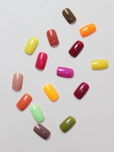 Flat lay of colorful glossy short false nails in 15 vibrant shades for nail art