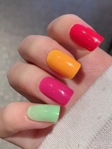 Vibrant square press-on nails in red and green with high-gloss finish on a hand