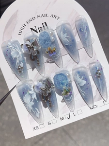 Detail of handmade press-on nails in blue gradient with 3D flowers and pearls