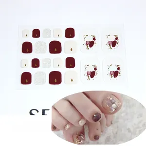 Macro detail of 5D glitter toe nail stickers in dark red and silver with gold accent gems