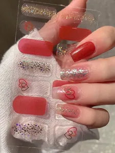 Close-up of glittery red and gold heart nail stickers applied on manicured fingernails