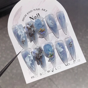 Handmade stiletto press-on nails with blue cat-eye glitter and floral 3D charms