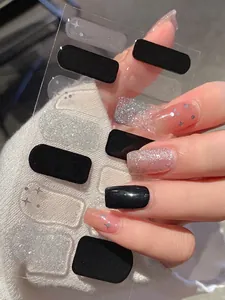 Detail von schwarz-silbernen Nagelaufklebern mit Sternenmustern auf Strickhintergrund