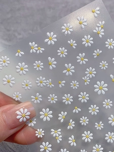 Macro detail of 3D embossed daisy nail stickers with white petals and yellow cores