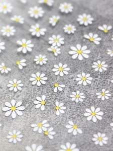 Macro shot of 3D embossed daisy nail stickers in various sizes with white and yellow ink