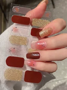 Detailed view of burgundy and gold glitter nail wraps with star patterns and blush finish