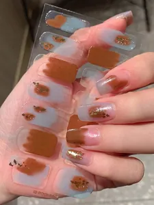 Close-up of caramel and grey-blue nail stickers with gold foil and smudge effect