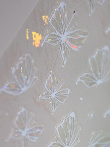 Macro view of 3D embossed butterfly nail stickers with laser glitter and white outlines