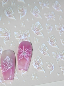 Macro detail of 3D butterfly nail decals on pink cat-eye polish and gradient nails