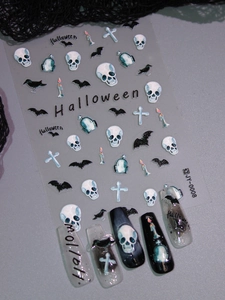 Macro detail of Halloween nail art stickers with skulls and bats on a long nail set