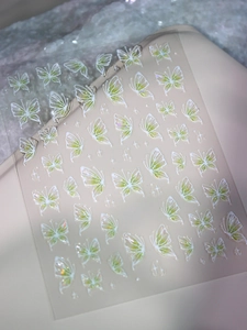 Macro detail of 3D embossed green gradient butterfly nail decals with starlight patterns