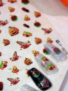 Detail of Halloween nail decals featuring matte pumpkin and candy designs on black nails