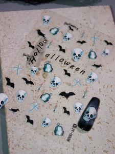 Detailed view of Halloween nail art stickers with skulls, bats, and blue matte finish