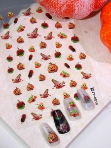 Macro detail of Halloween nail stickers with pumpkins and candies on marble surface