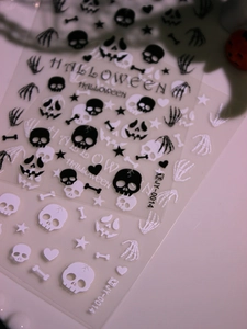 Macro shot of 3D Halloween nail stickers featuring skulls, bones, and pumpkin motifs