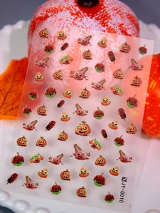 Macro shot of Halloween 3D nail stickers featuring pumpkins and candies on a white tray