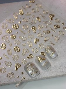 Close-up of gold embossed nail stickers with melting smiley faces and star designs