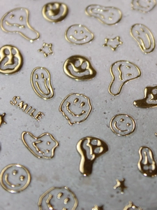 Macro shot of gold melting smile and star 3D embossed nail art stickers with metallic finish